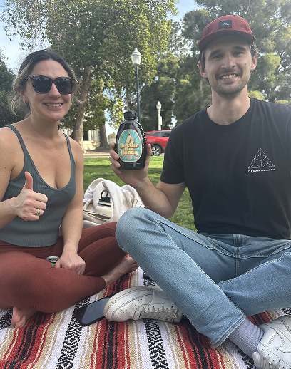 Couple enjoying Better Than Honey molasses outdoors on a picnic